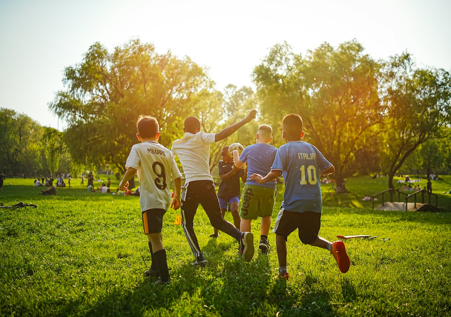 Ragazzi che giocano a calcio su un prato soleggiato nel parco.